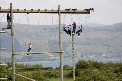 Students hanging from ropes with safety harness at Adventure Park