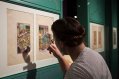Woman examins Medieval Artwork through a magnifying glass
