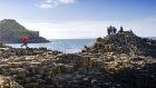 Student skipping stones towards the group of collegues standing on the top of  the Giant's Causeway Pillars 