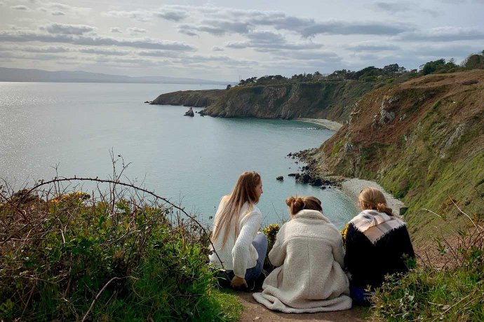 Group of Students on a Walking Tour by The Coast Resting