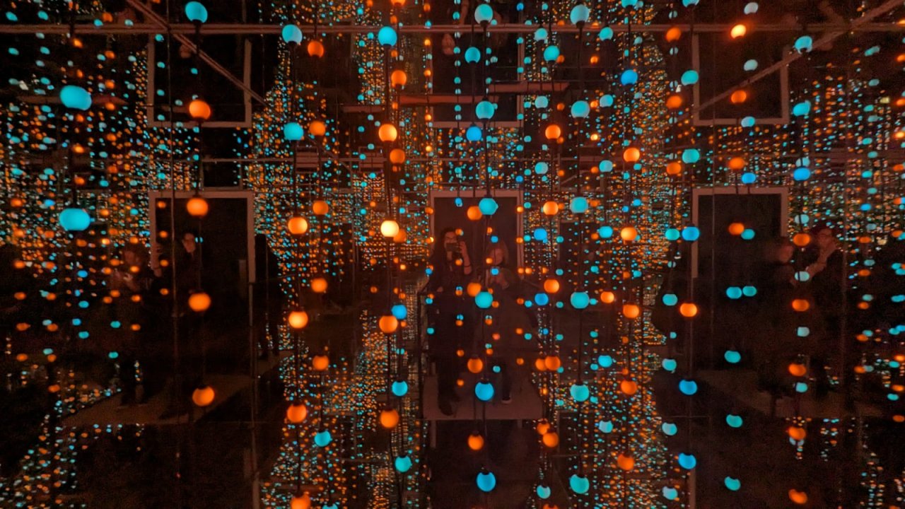 School visitors experiencing infinity room with multi-coloured light strings in mirrored room creating  infinity effects for educational purposes 