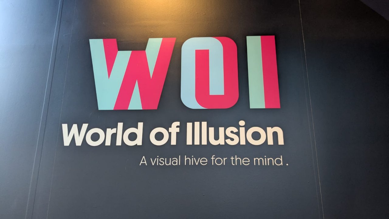 WOI - World of Illusion - A visual hive for the mind Logo with strapline on a dark background letters WOI  in pink and blue create 3d shape shifting effect