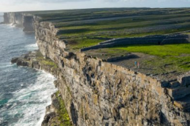 Inis Mór, Aran Islands - Dun Aengus Ancient Fort with two visitors standing by the cliff