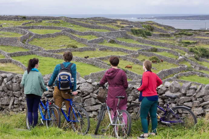 Group of students on a bike trip watching ancient island green fields landscape