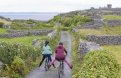 Two Students on a downhill road among ancient fields on an island with stone build castle view in the background on the right