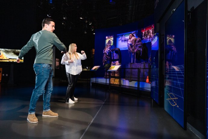 Two people playing using their bodies on the front of the giant interactive screens in GoT filming studio during a self-guided tour