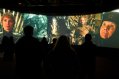 Big Screen Displaying Scenes from TV Series GoT with Shadows of People Visible In The Dark Room