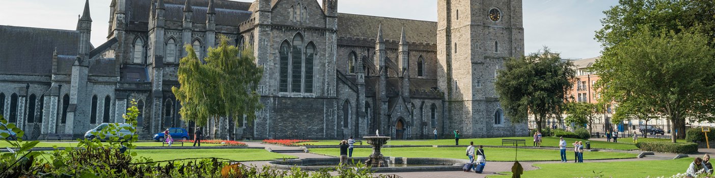 On a sunny day, people walk by St. Patrick's Cathedral, featured on Dublin's Christian Legacy Tour