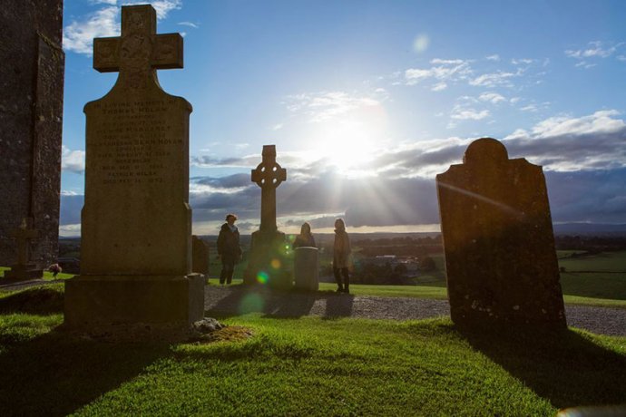 A group of tourists viewing the tombstones with celtic crosses