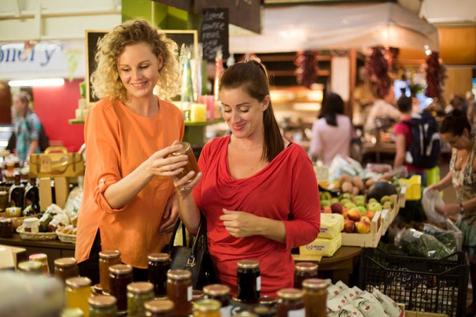 Two women choosing from a sellection of jams