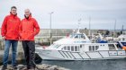 Doolin Pier - two man wearing red jackets standing on a front of the boat Doolin Express with a blue writing on a cabin DoolinFerry.com