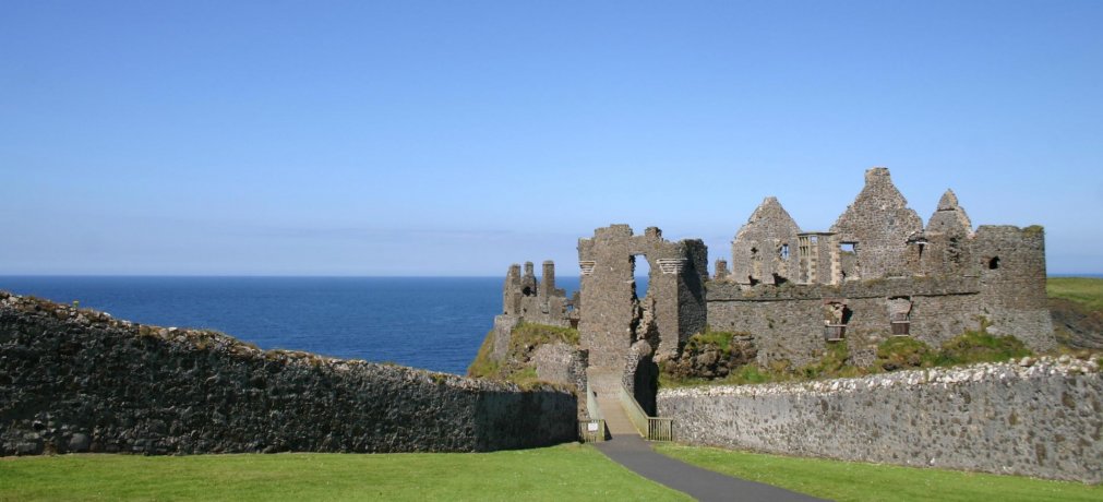 Dunluce Castle in Northern Ireland in Full Sunshine with Blue Sky Above and Ocean in the Background