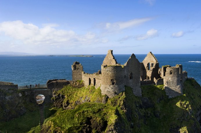 View of the Dunluce Castle Complex with Bridge and Full View of The Ruin in the Sunshine with Ocean View at the Back