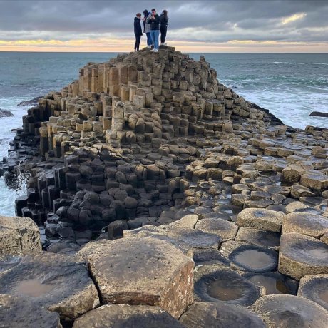 A group of students on a walking tour at the top of the partially submerged basalt hill on the coast