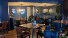 restaurant space with blue walls, square brown tables, 2 blue semi-circular sofas, brown chairs. Food for groups in Dublin city hostels