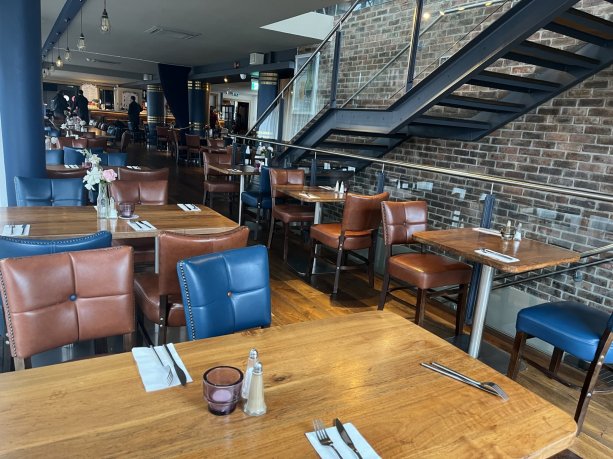 group eating area with brown tables and blue chairs, brown floor, brick walls. Right for budget meals in Dublin for school groups, student trips and sport teams