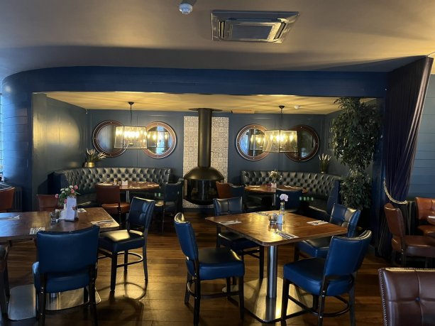 Harbourmaster restaurant area with blue chairs, brown tables, blue wall. Budget meals for school groups, student trips and sports team