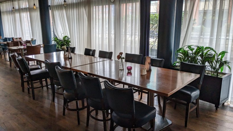 group dinning area with brown rectangular tables, blue chairs, window walls with white curtains. Ideal for group meals in Dublin city centre