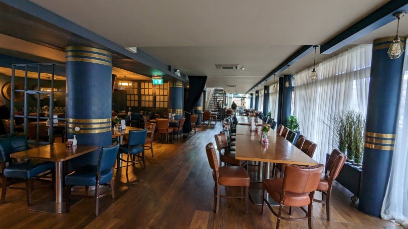 restaurant area with rectangular brown tables, brown chairs, brown floor, blue cylindrical pillars. Suitable for groups staying in Dublin city.