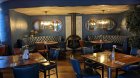 Restaurant area with blue walls, brown floor, 2 blue semi-circular sofas, brown tables and chairs.  Right for school groups, student trips and sport teams