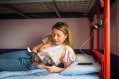 Student Girl Reading Brochure on a Bunk Bed in Hostel