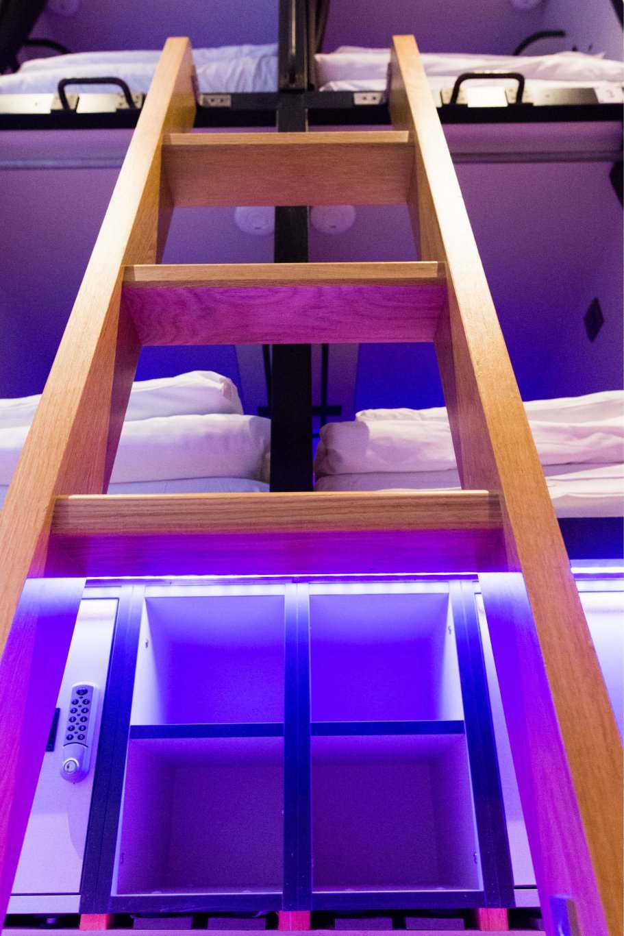 access ladder to upper capsules in pod hostel brightly lighted