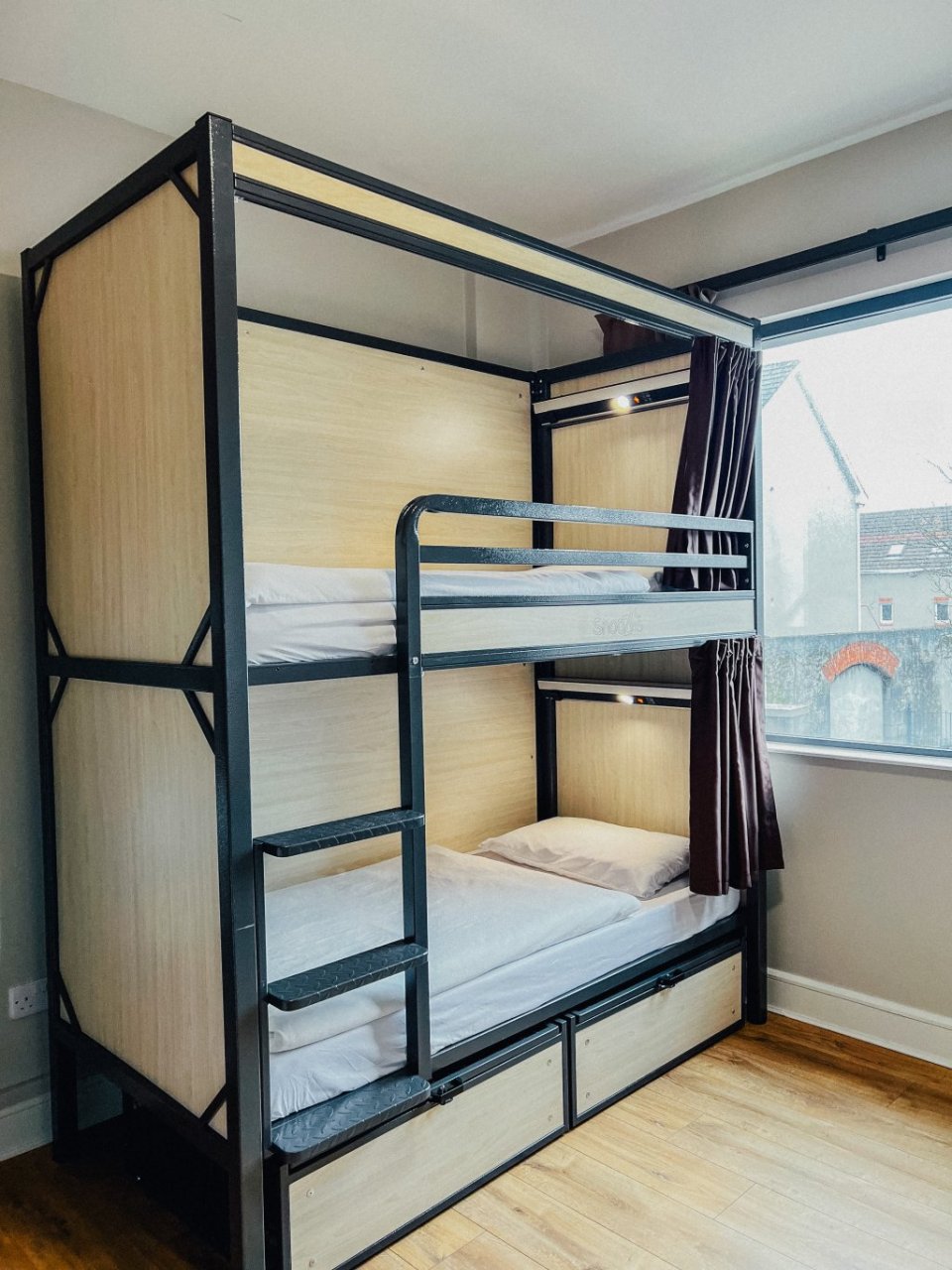 Cream-coloured Bunk Beds with Privacy Curtains by the Window in Modern Student Group Hostel