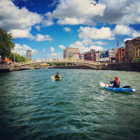 Students kayaking on the river passing under the Ha'Penny bridge
