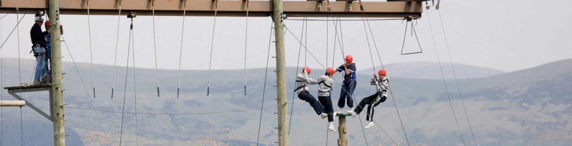 Group of students on a high ropes climbing session with the mountains in the backdrop