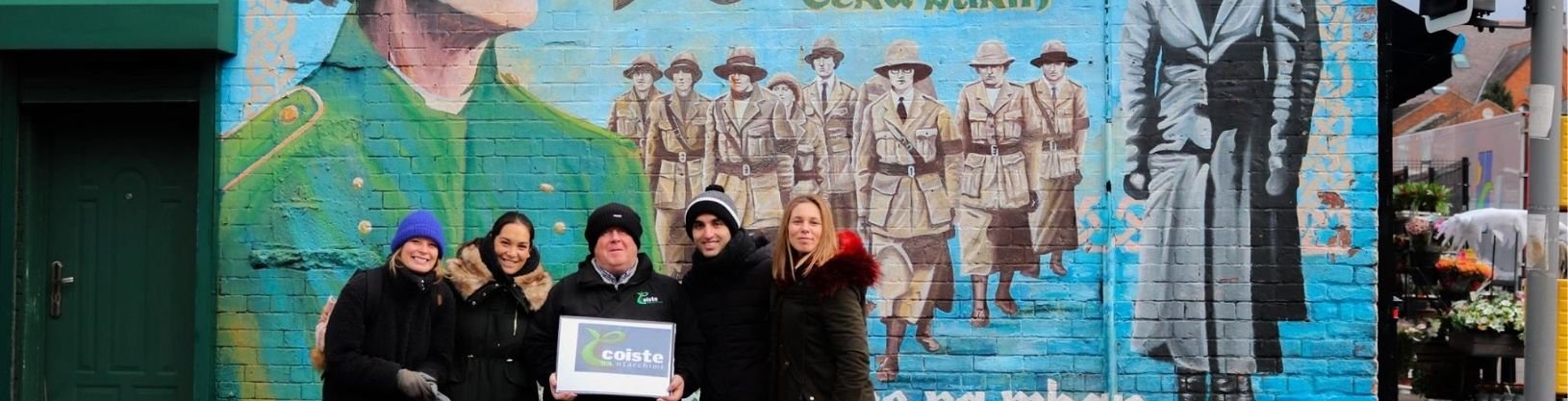 Students with Coiste guide standing in front of political mural in Belfast